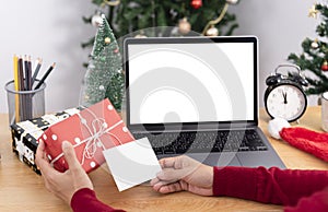 Business woman holding giftbox and greeting card on office table in Christmas day