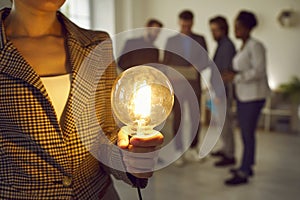 Business woman holding glowing light bulb in hand, brainstorming, creative ideas concept.