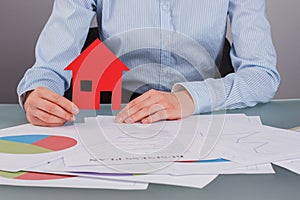 Business woman holding house model working at office.