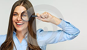 Business woman holding magnifying glass behind eyes.