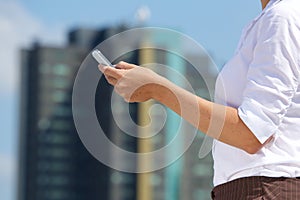 Business woman holding mobile phone in the city
