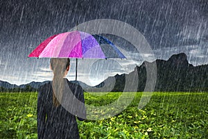 Business woman holding multicolored umbrella with falling rain at Khao Jeen Lae