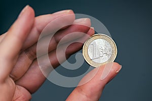 Business woman holding one euro coin between fingers