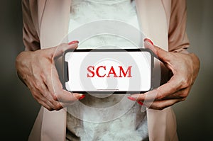 Business woman holding phone with text scam. Internet security, fraud warning concept