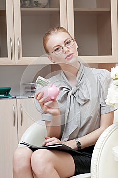 Business woman holding piggy bank containing one dollar.