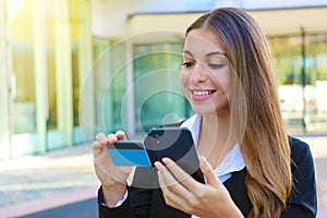 Business woman holding smart phone reading credit card number making shopping online outdoor office on break time. People and