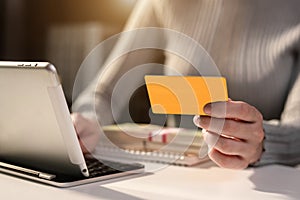 Business woman holds a credit card and transact with a tablet at home.