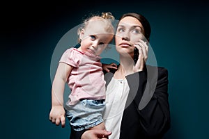 Business woman holds her little daughter in her arms. Careerist and motherhood