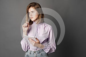 Business woman holds a notebook with a pen. Something writes and thinks. Studio photography. One on a gray background.