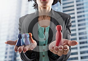Business woman holds wooden toy shaped as person. Concept of business teamwork and leadership