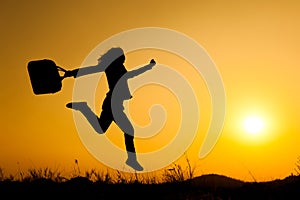 Business woman jumping and holding bag sunset silhouette photo