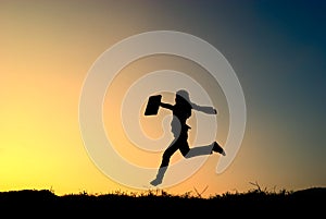 Business woman jumping and sunset silhouette