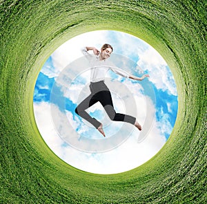 Business woman jumps in rotated field with green grass.