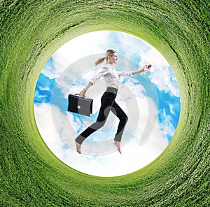 Business woman jumps in rotated field with green grass.