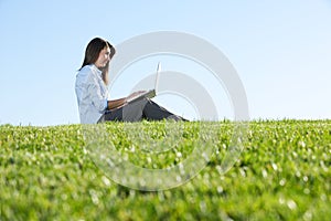 A business woman on a laptop in a field