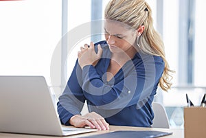 Business woman, laptop and shoulder pain suffering from work injury, accident or ache at the office desk. Female