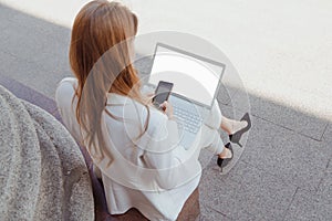 Business woman with laptop working outdoors. Laptop blank screen mockup.