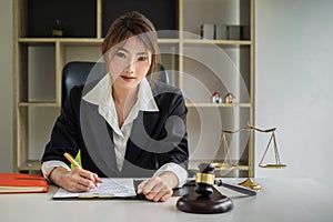 Business woman or lawyers discussing contract papers with brass scale on wooden desk in office. Law, legal services, advice,