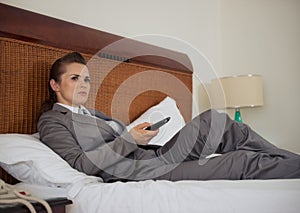 Business woman laying on bed and watching tv