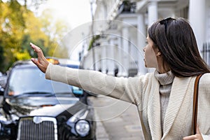 Business woman in London hailing for a black taxi