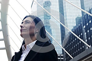 Business woman look up sky and offices building in the city.