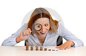 Mujer de negocios mira a creciente pila de monedas a través de vaso 