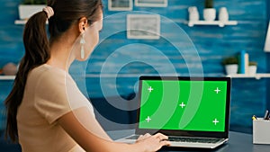 Business woman looking at laptop display with mock up green screen