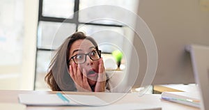 Business woman looking out from behind her desk in office