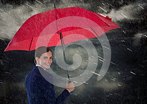 Business woman looking over shoulder with umbrella against rainy sky