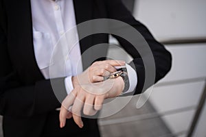 A business woman looks at her wristwatch. Close-up