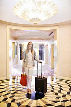 Business woman, luggage and smile in hotel corridor for portrait with suit, handbag and pride in lobby. Person