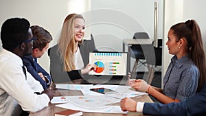 Business woman makes a presentation with charts, diagrams for multiethnic partners. Startup team discuss project plan