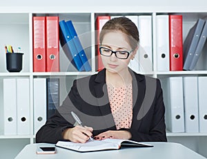 Business woman making notes at office workplace.