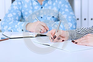 Business woman making notes at office workplace with male colleague at the background. Business job offer, financial