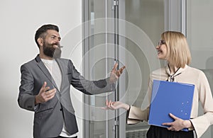 Business woman and man colleagues in office. Bearded man talk to sensual woman with binder. Office workers wear formal