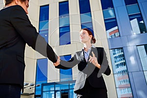 Business woman and man shaking hands outdoors. Business cooperation concept