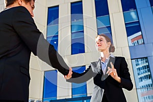 Business woman and man shaking hands outdoors. Business cooperation concept