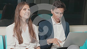 Business woman and man sitting using laptop computer working talking together on the subway train