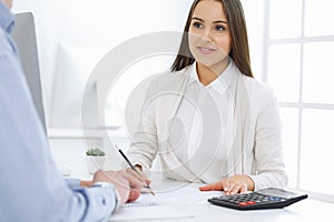 Business woman and man sitting and working with computer and calculator in office. Bookkeeper or accountant checking