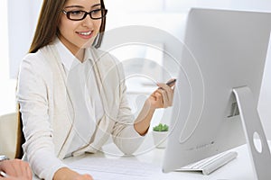 Business woman and man sitting and working with computer and calculator in office. Bookkeeper or accountant checking