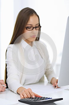 Business woman and man sitting and working with computer and calculator in office, close-up of hands. Bookkeeper or