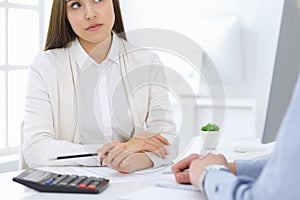 Business woman and man sitting and working with computer and calculator in office, close-up of hands. Bookkeeper or