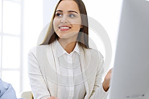 Business woman and man sitting and working with computer in office. Colleagues discussing something at meeting