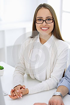 Business woman and man sitting and working with computer in office. Colleagues discussing something at meeting