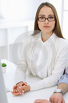 Business woman and man sitting and working with computer in office. Colleagues discussing something at meeting