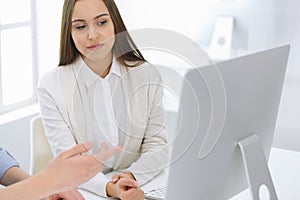 Business woman and man sitting and working with computer in office. Colleagues discussing something at meeting