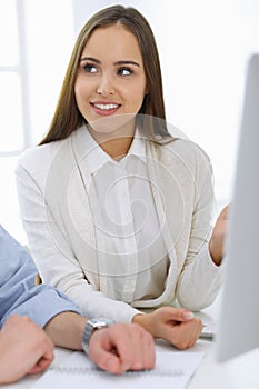 Business woman and man sitting and working with computer in office. Colleagues discussing something at meeting