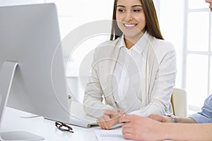 Business woman and man sitting and working with computer in office. Colleagues discussing something at meeting