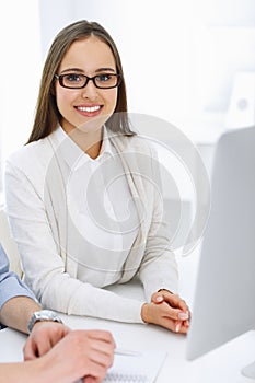 Business woman and man sitting and working with computer in office. Colleagues discussing something at meeting