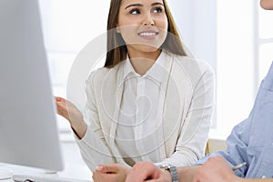 Business woman and man sitting and working with computer in office. Colleagues discussing something at meeting